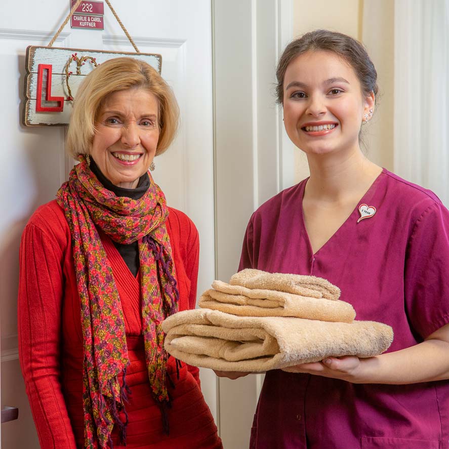 A team member delivering fresh linens to a resident at Magnolia Heights